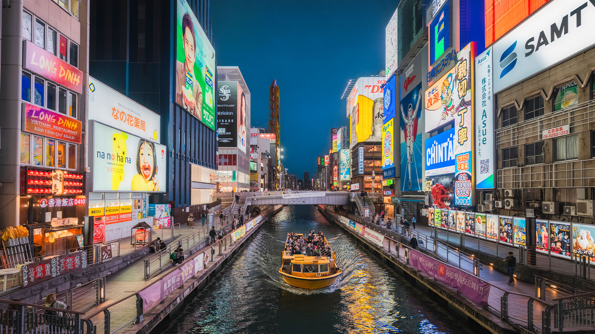 Bright neon signs surrounding a canal at night