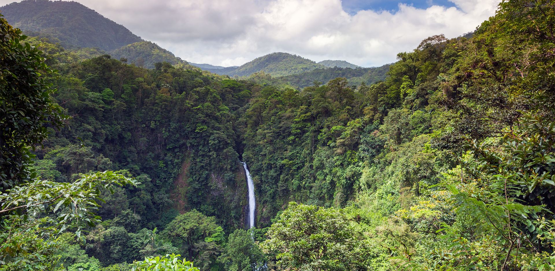 Aerial view of La Fortuna waterfall amid lush forests.