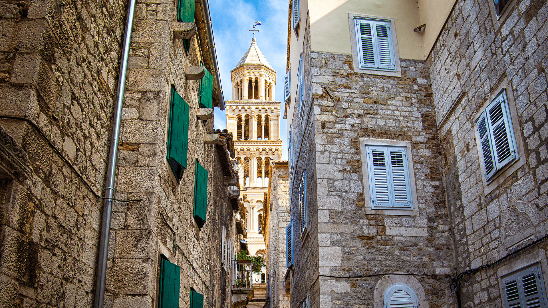 Narrow stone alley in Split with bell tower view