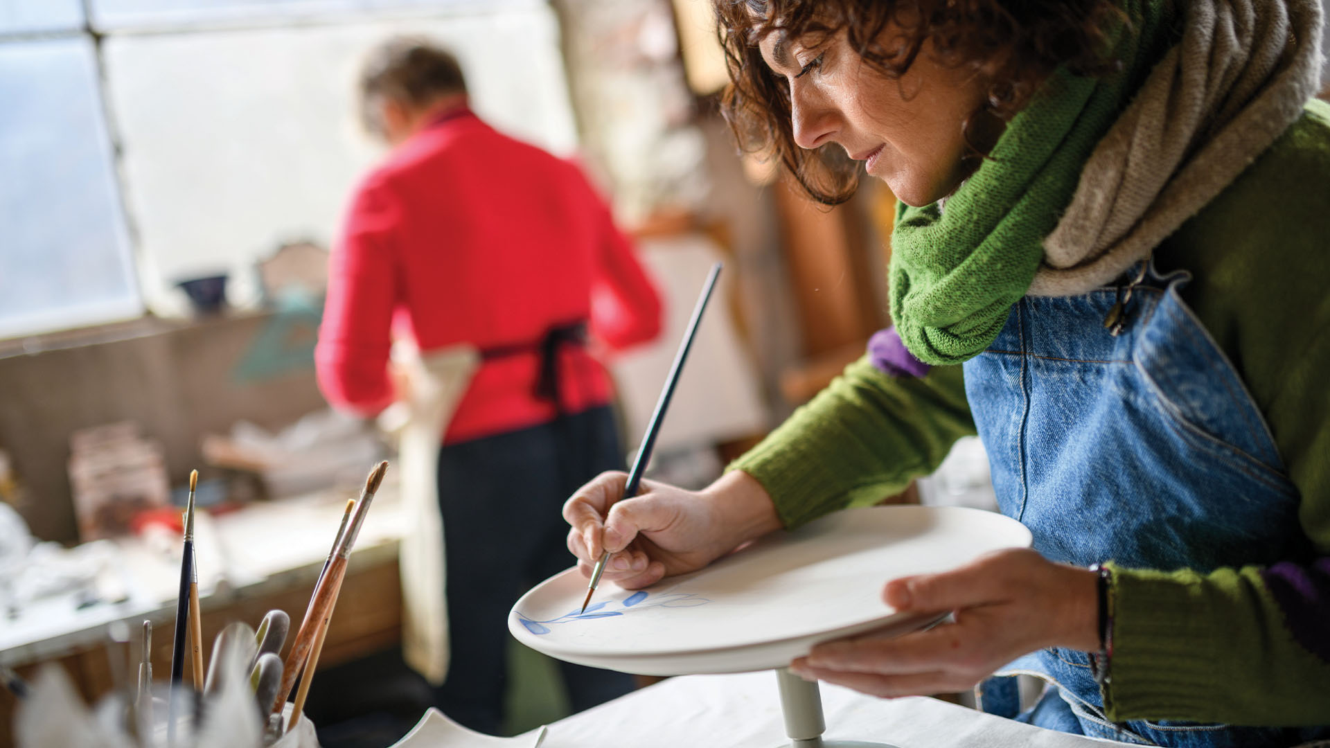 Woman painting on clay in pottery class