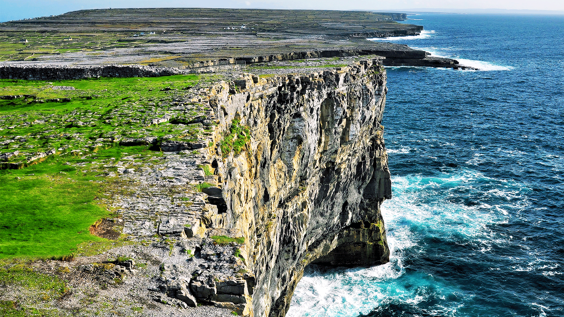 Aerial view of cliffs meeting the sea on a sunny day