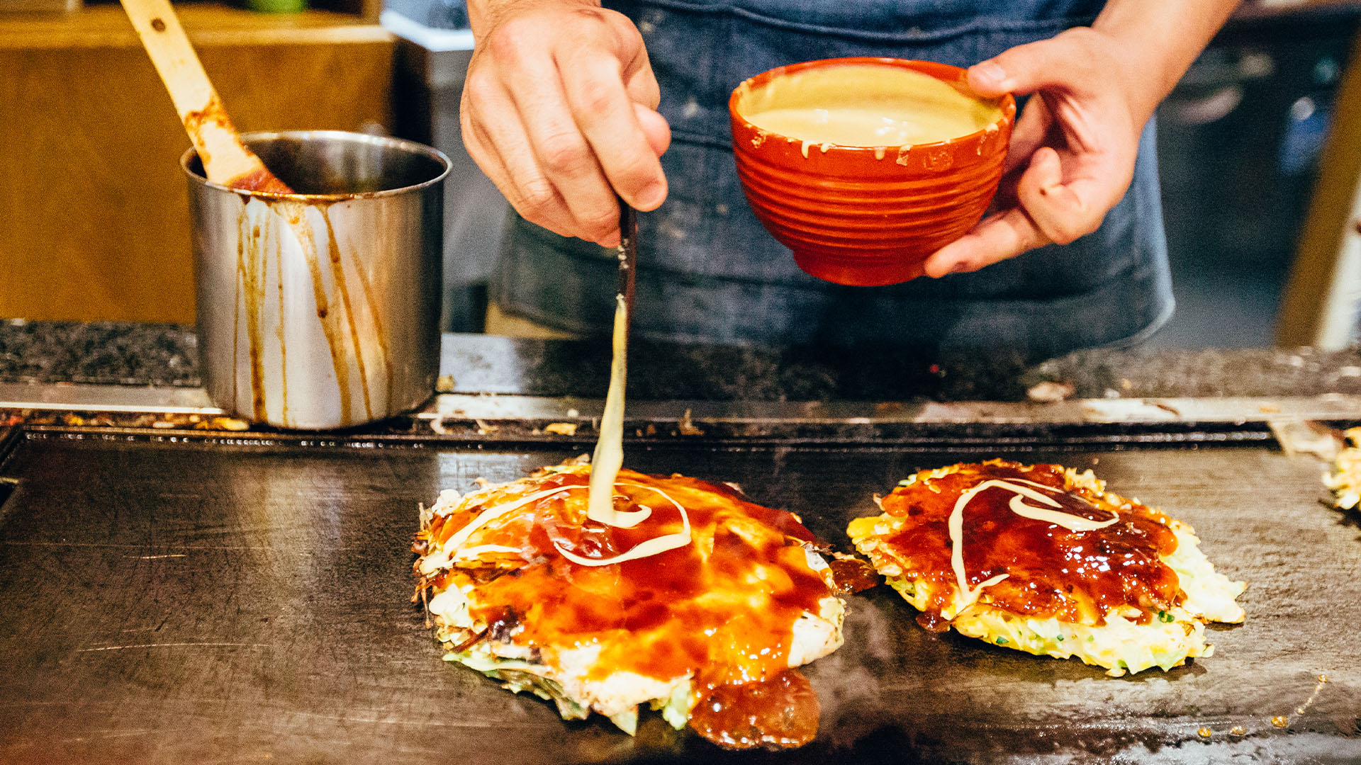 Chef cooking okonomiyaki on a flat grill 
