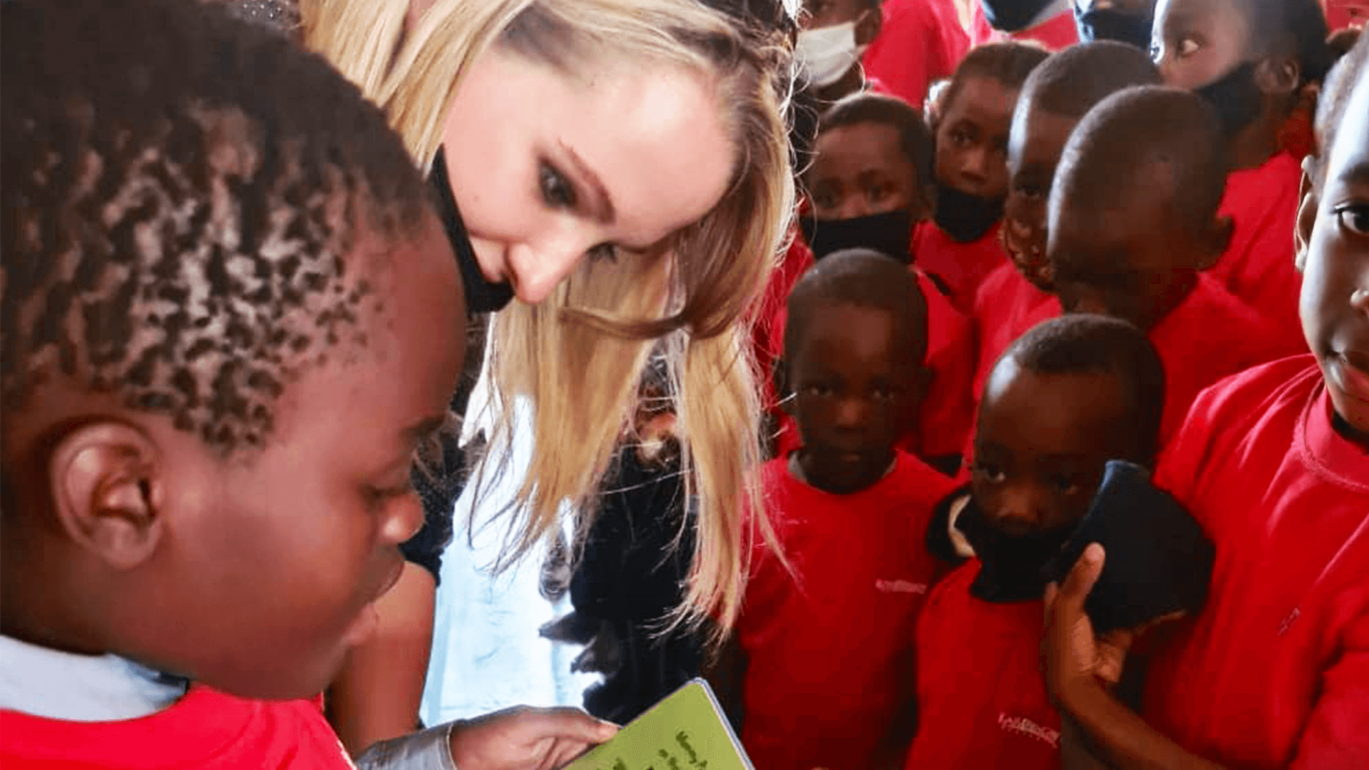 A woman reads a book to a group of local school children
