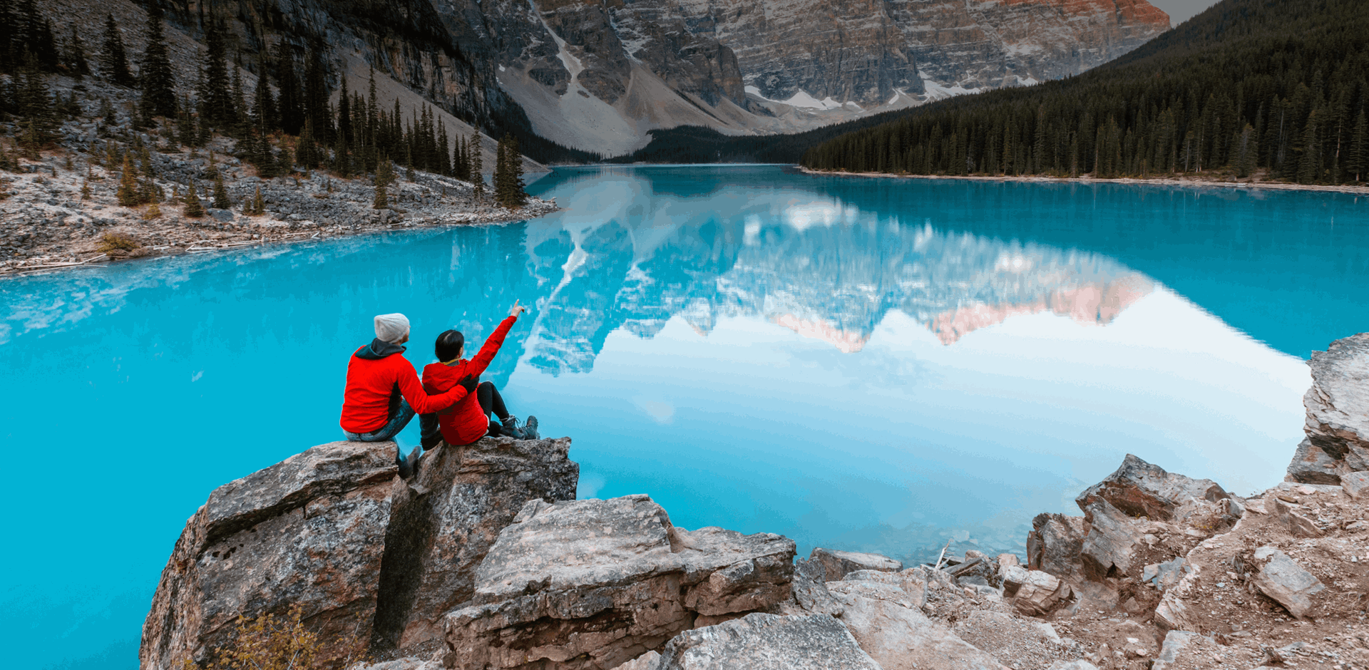 Couple looking at piercing blue Moraine lake and mountains, Banff, Alberta, Canada.