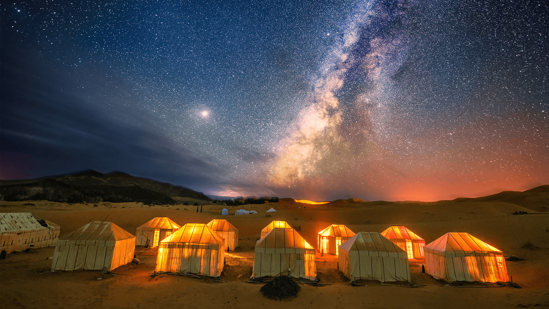 The Milky Way over tents in the Sahara Desert at night
