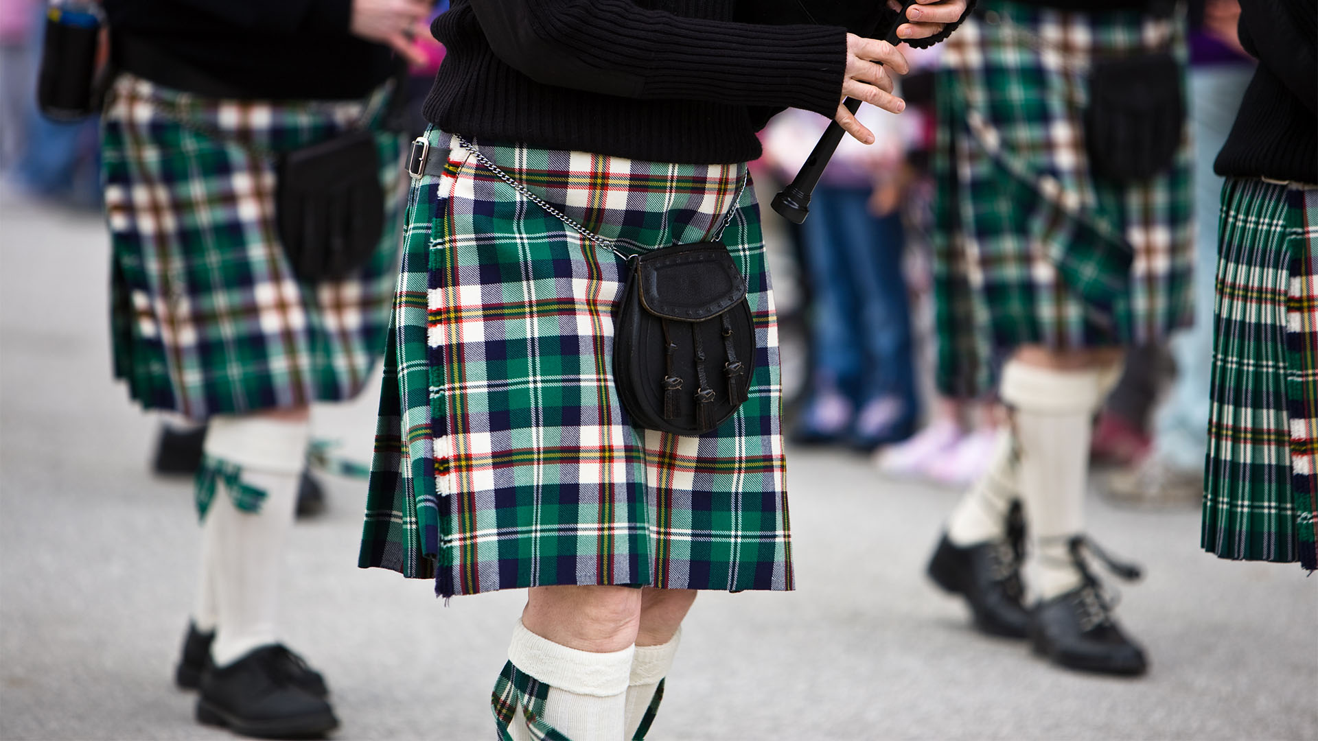 Close-cropped view of bagpipers marching in formation. 