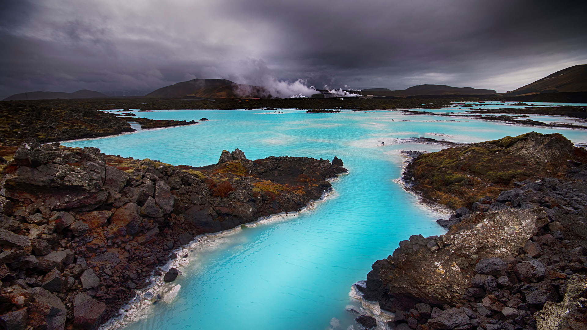 Clear blue waters of a thermal lagoon set against dark rocks