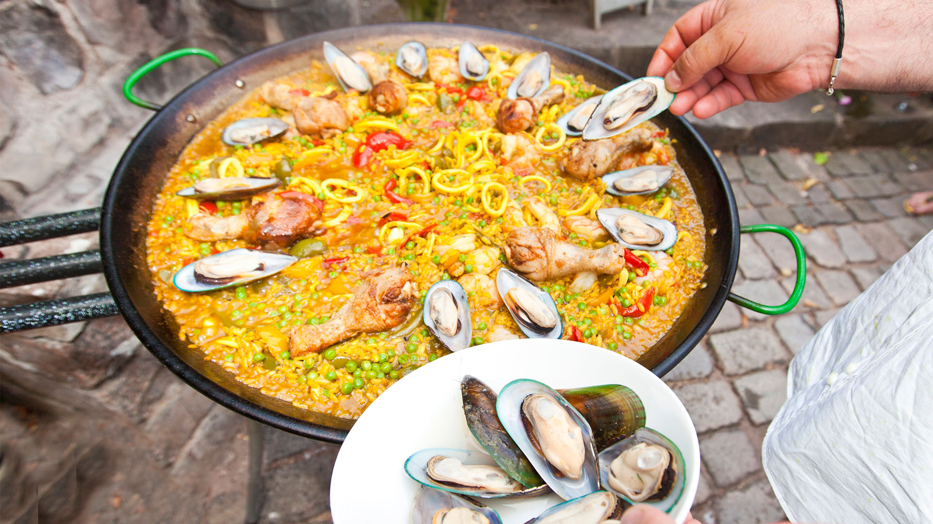 A cook preparing a seafood paella outdoors