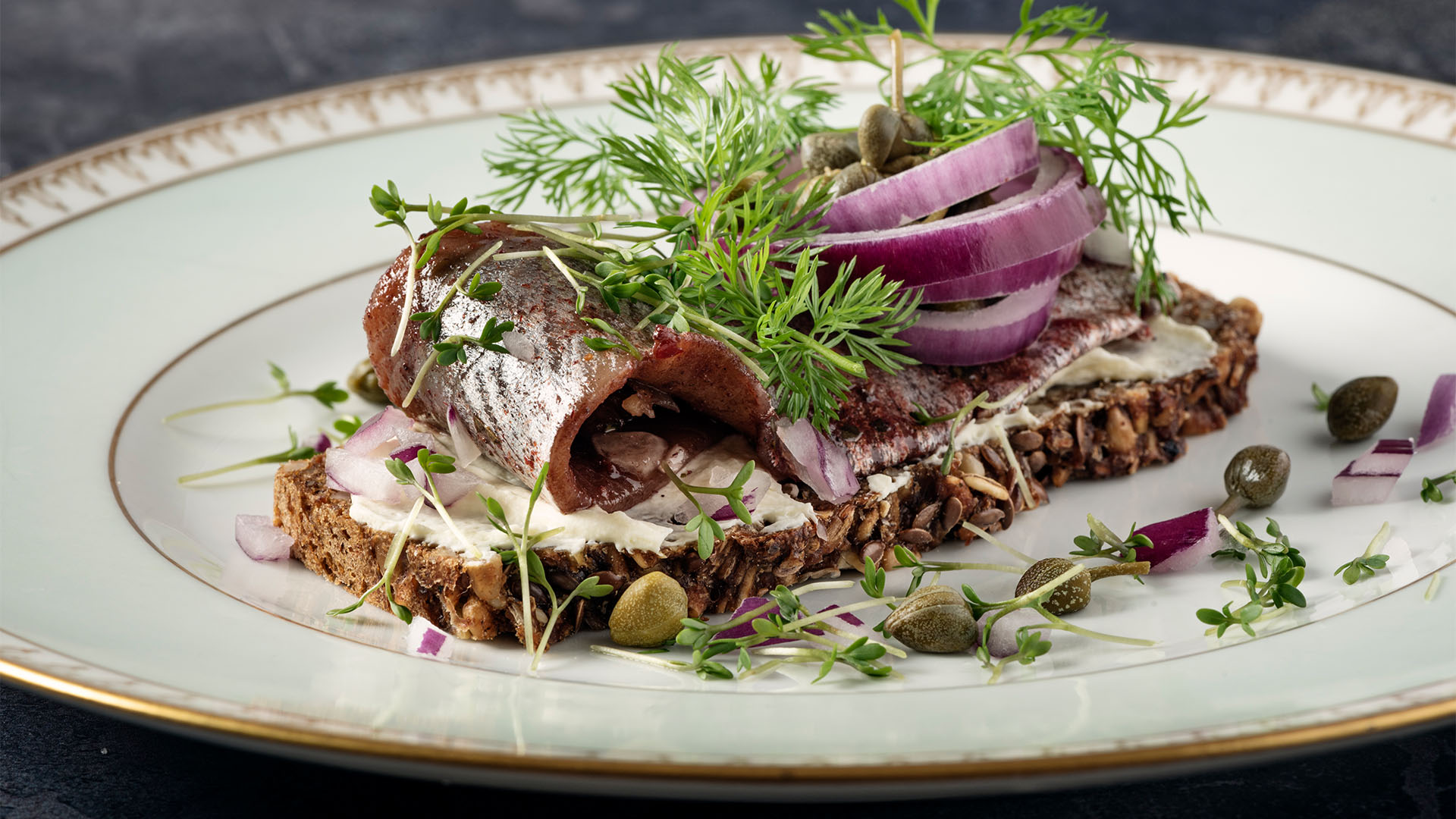 An open sandwich of pickled herring on buttered rye bread