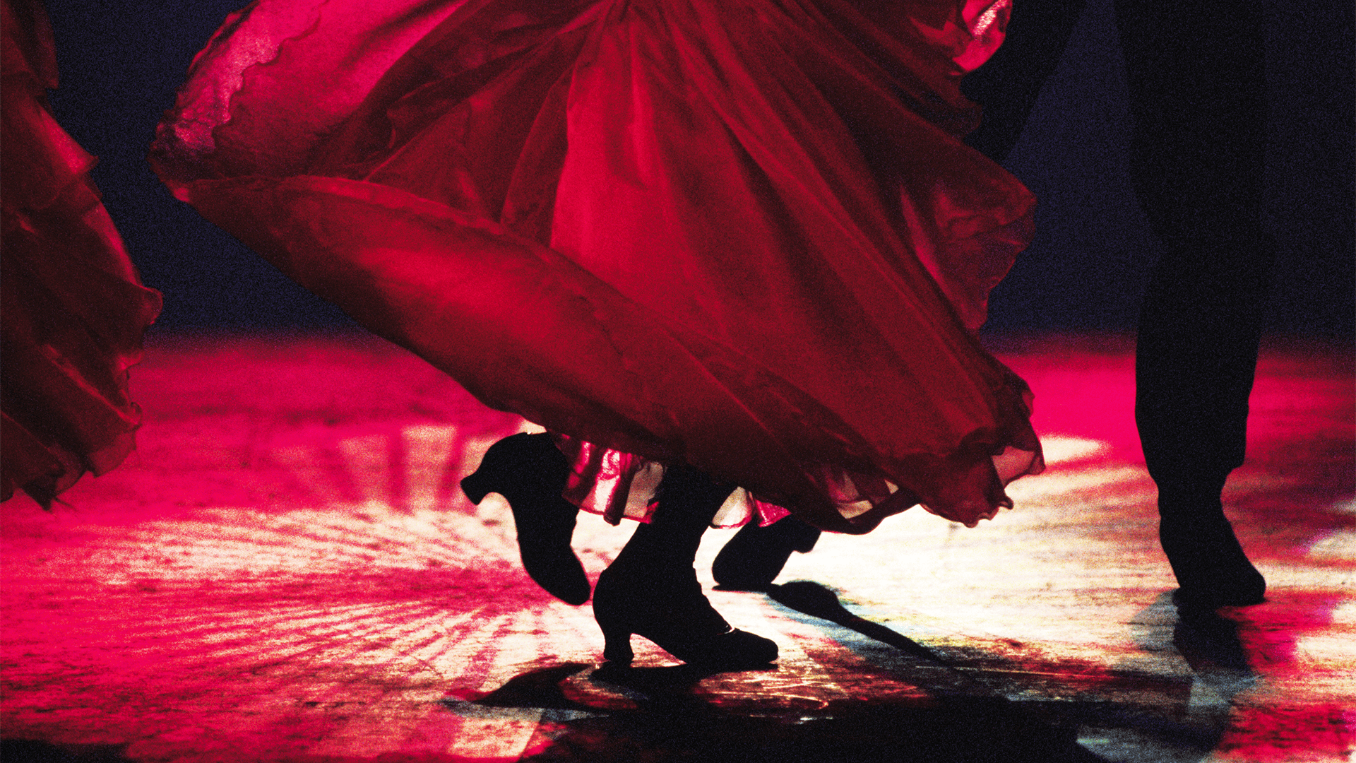 Flamenco dancers under dramatic red stage lighting