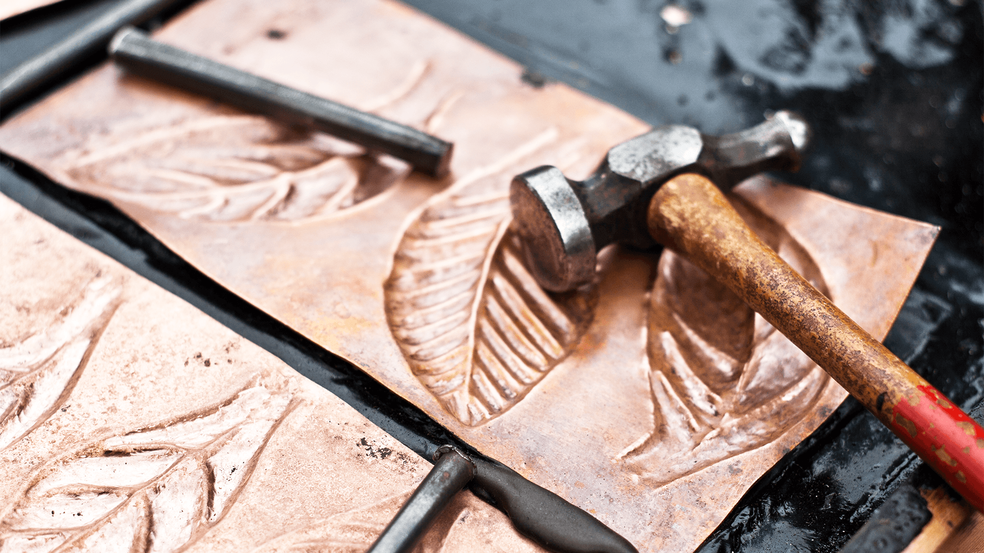 Close up of copper sheets with hammered leaf patterns