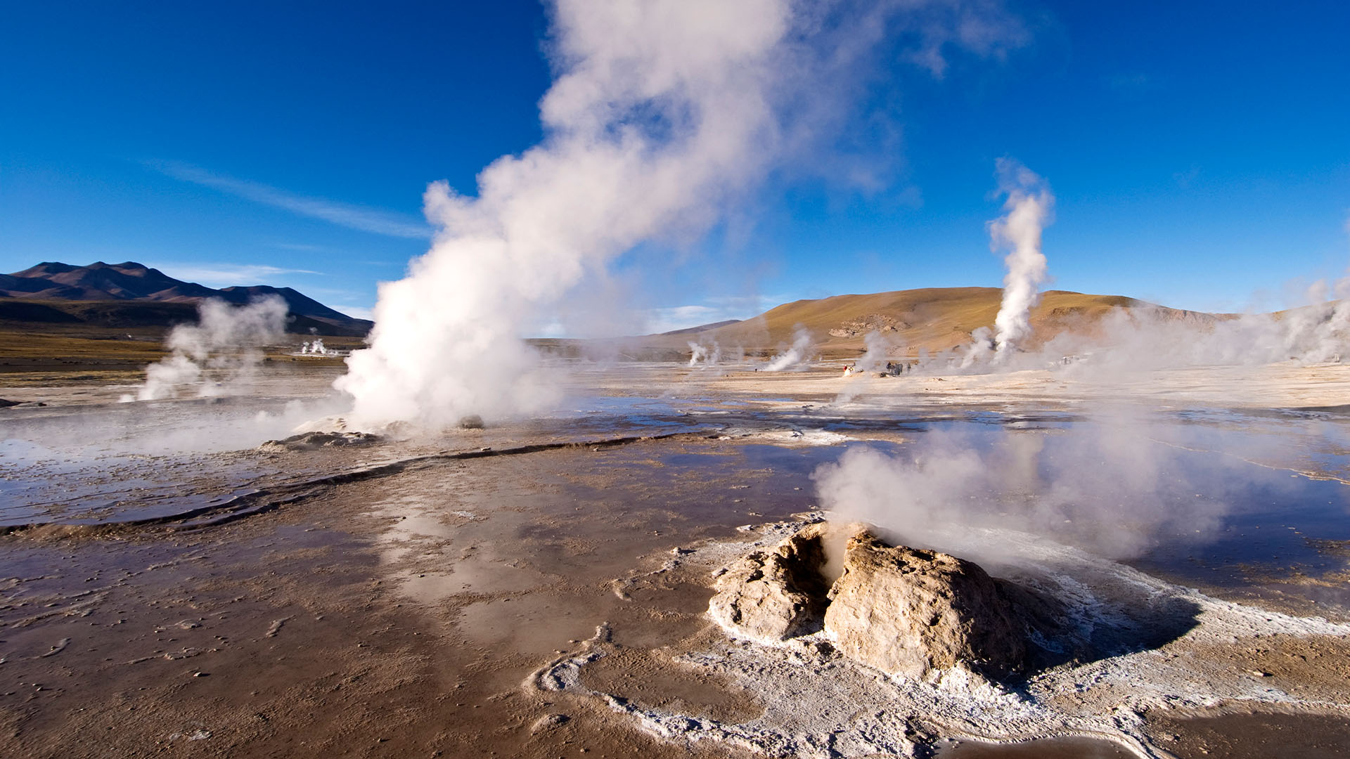 Desert landscape with multiple geysers blowing steam