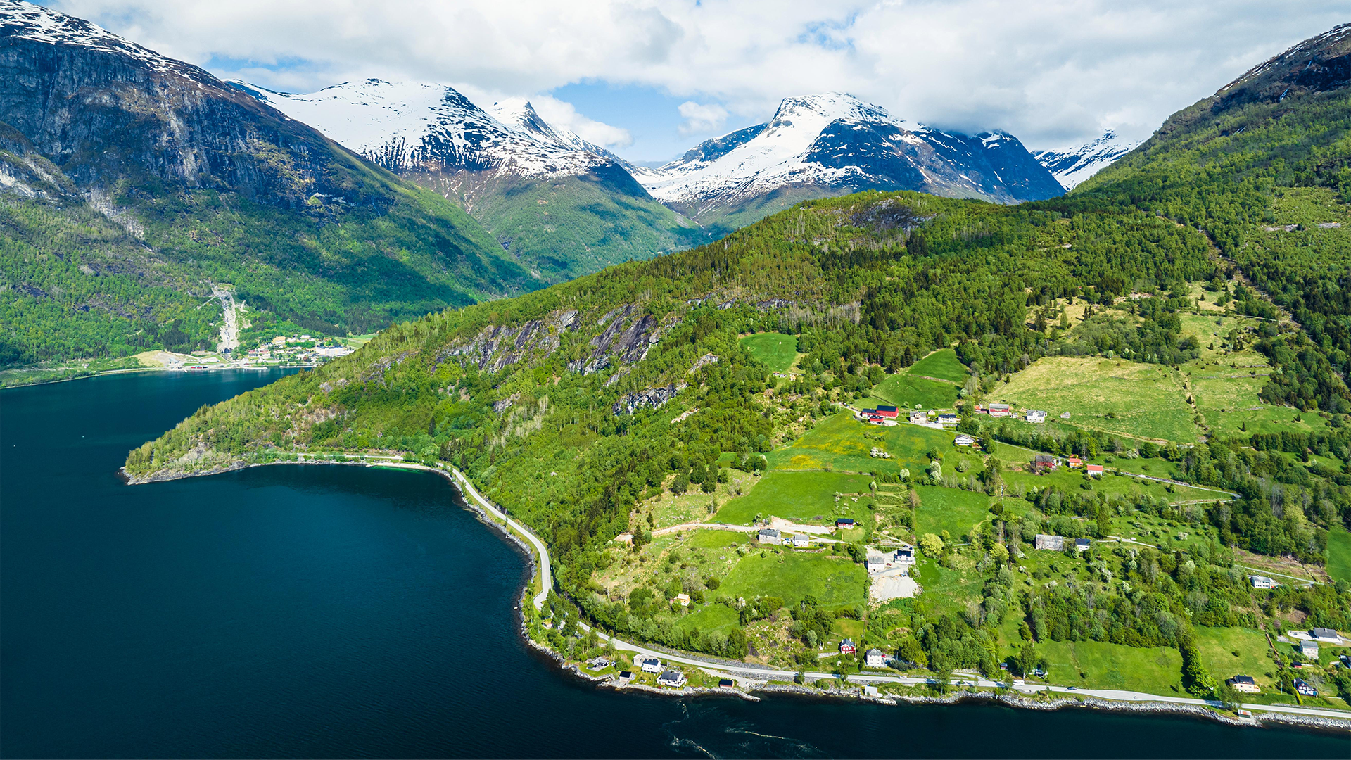Snow-capped mountains and green hills of a fjord