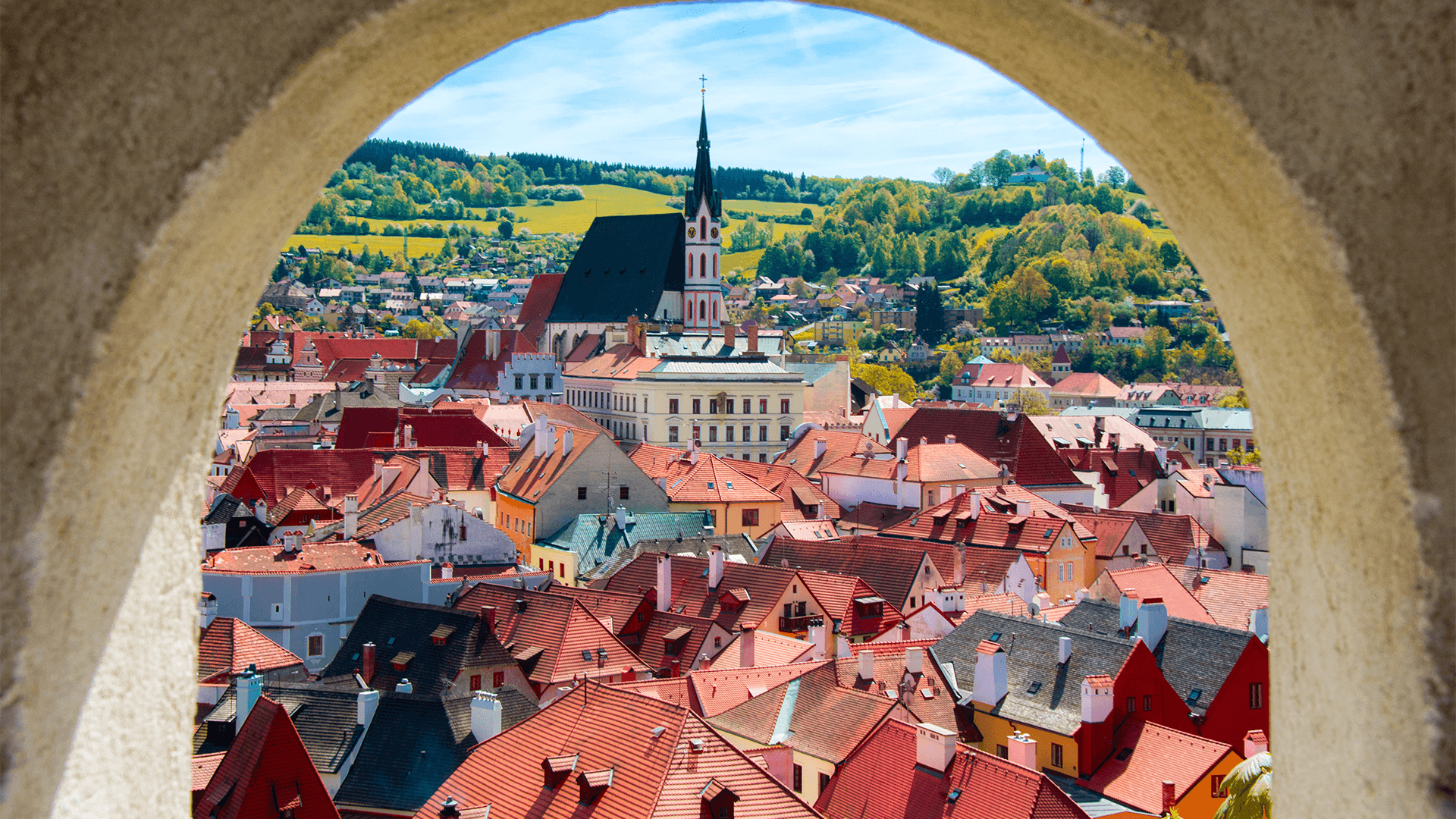Stone archway framing view of rooftops in Český Krumlov
